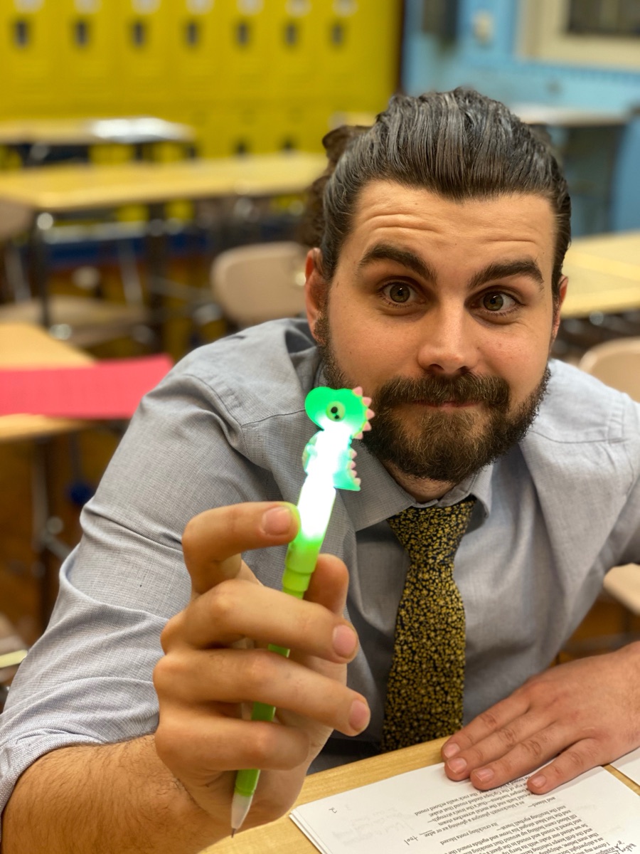 Connor Koblinski in his classroom holding a light-up dinosaur pen
